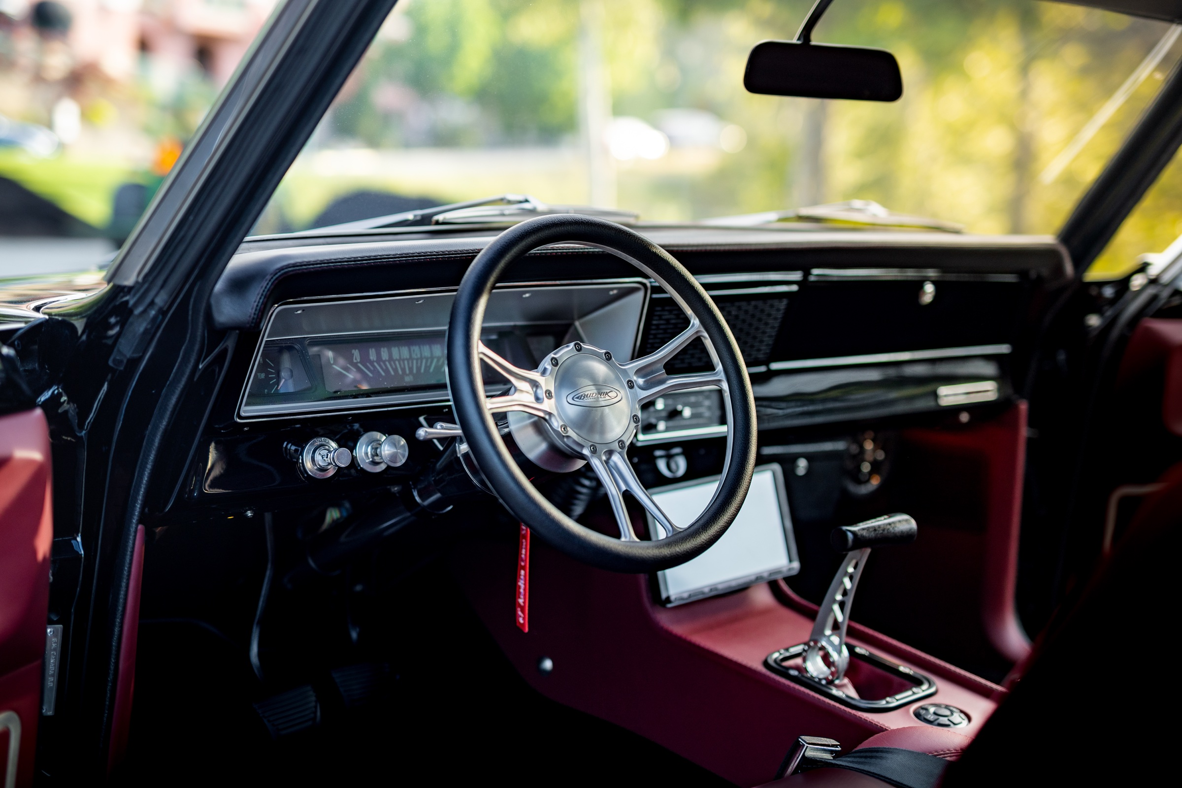 Custom steering wheel, dashboard, shifter, and burgundy cabin of the Acadian Canso