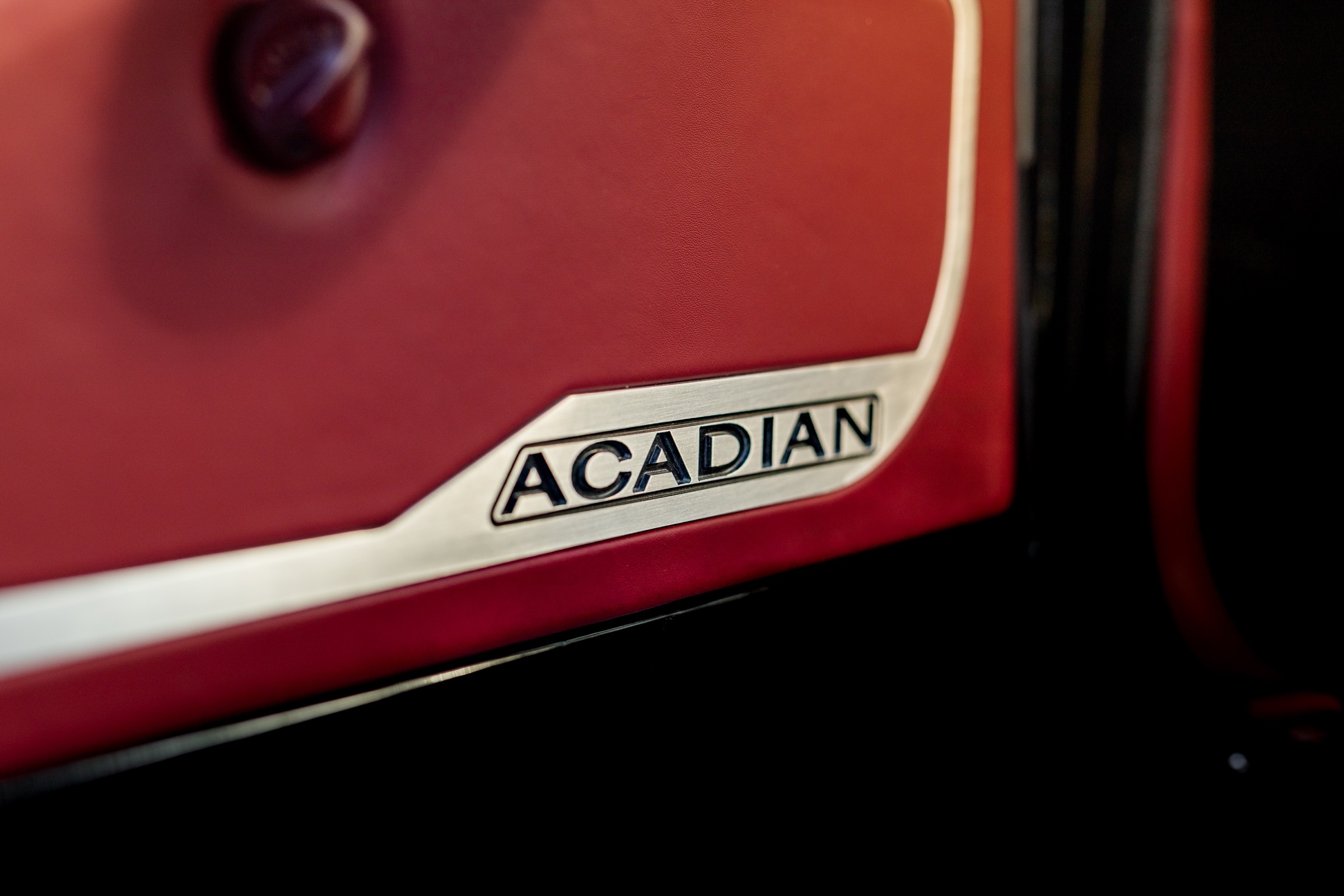 Acadian badge set into the burgundy interior door panel