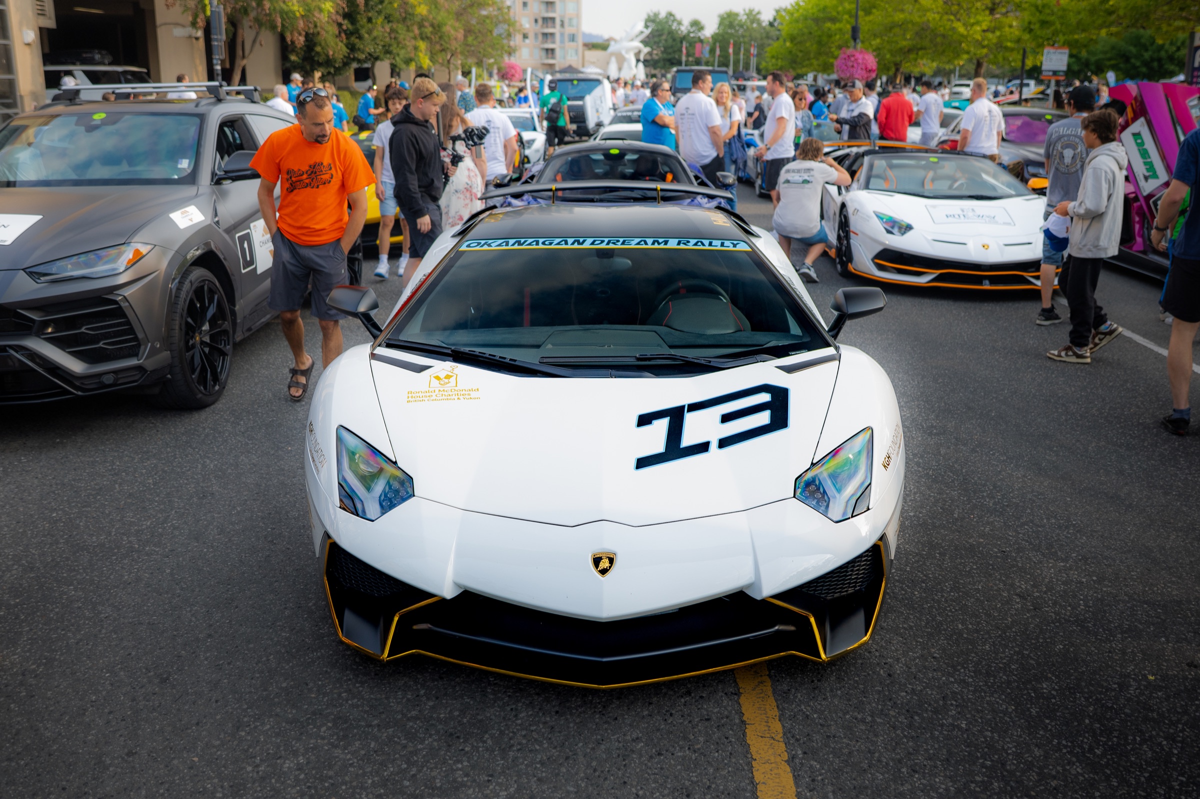 White Lamborghini Aventador number 13 surrounded by the downtown rally crowd