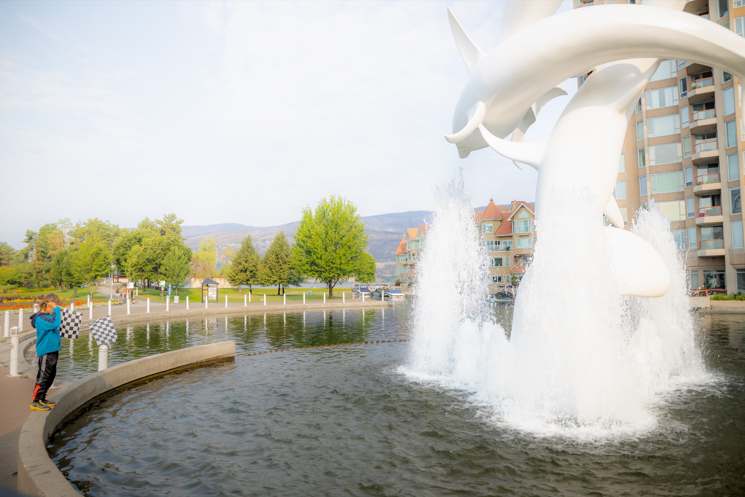 Kelowna waterfront sculpture and a young spectator holding chequered flags