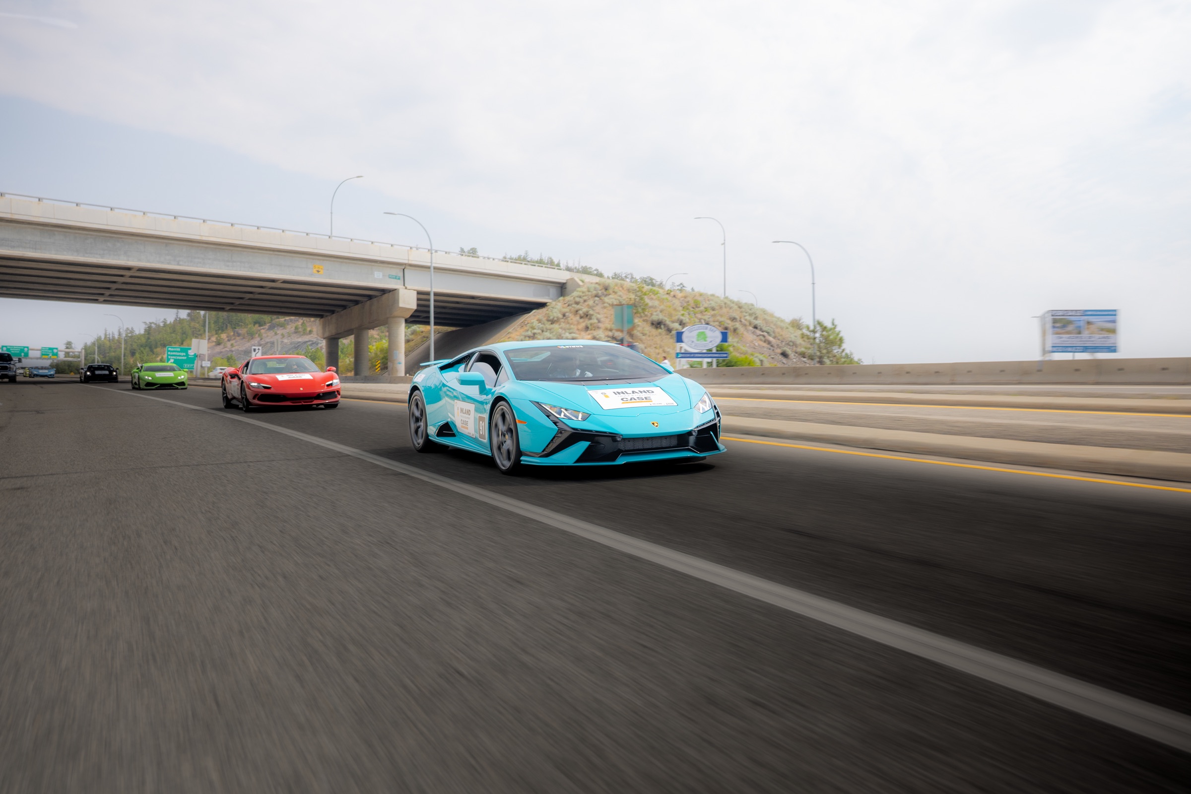 Turquoise Lamborghini Huracan leading exotic cars on Highway 97