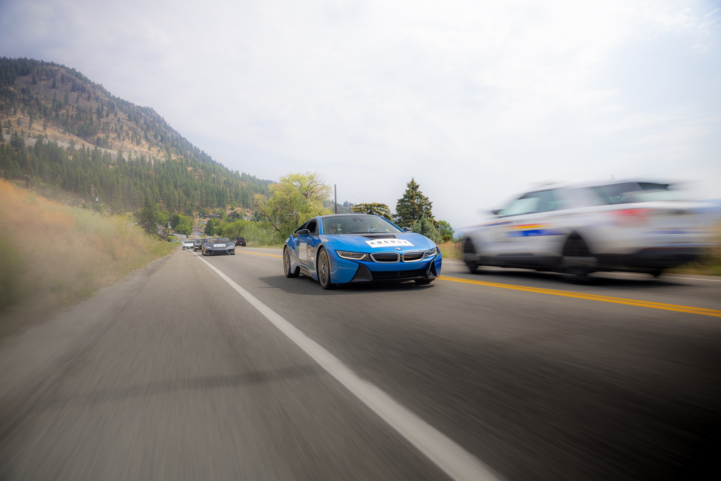 Blue BMW i8 driving past Okanagan mountains during the rally