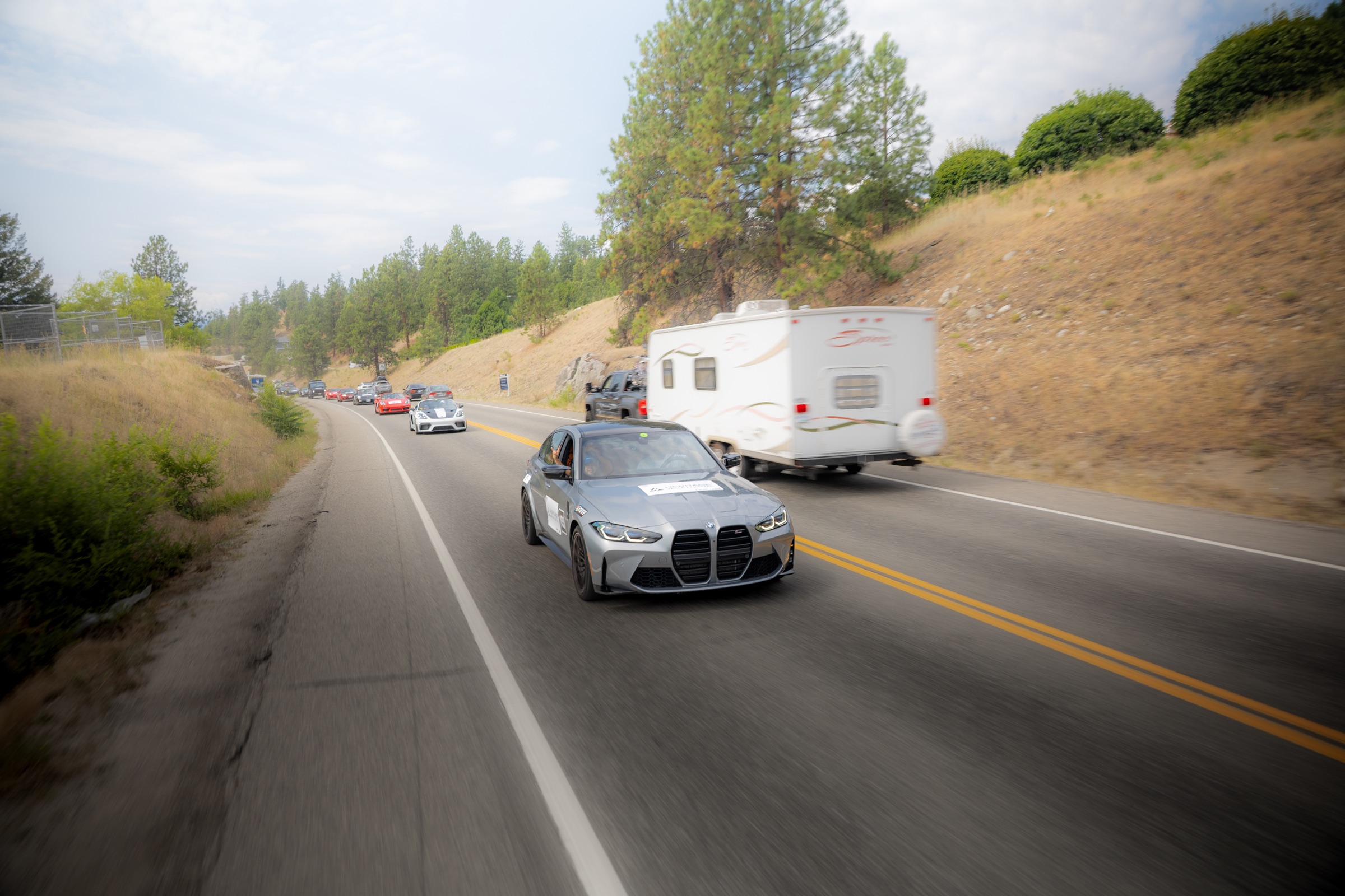 Grey BMW M4 leading the rally convoy along an Okanagan road