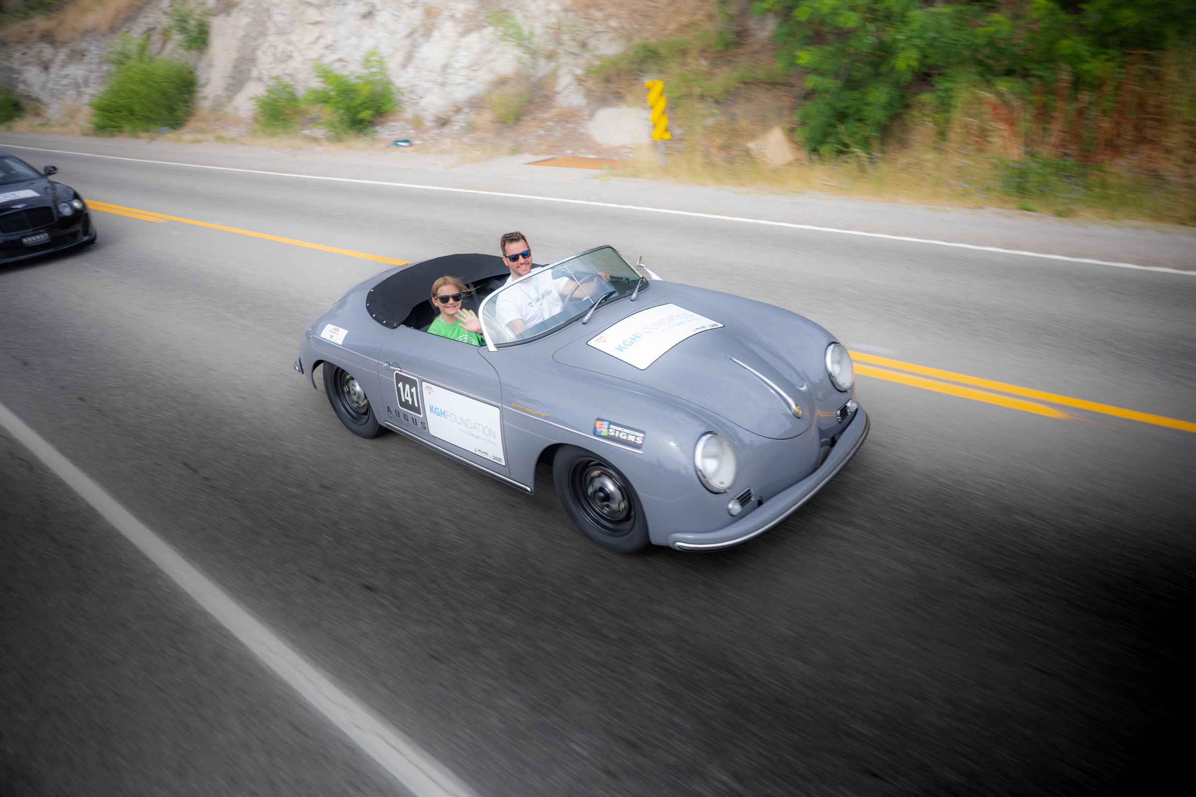 Grey Porsche 356 Speedster carrying a waving Dream Rally co-pilot