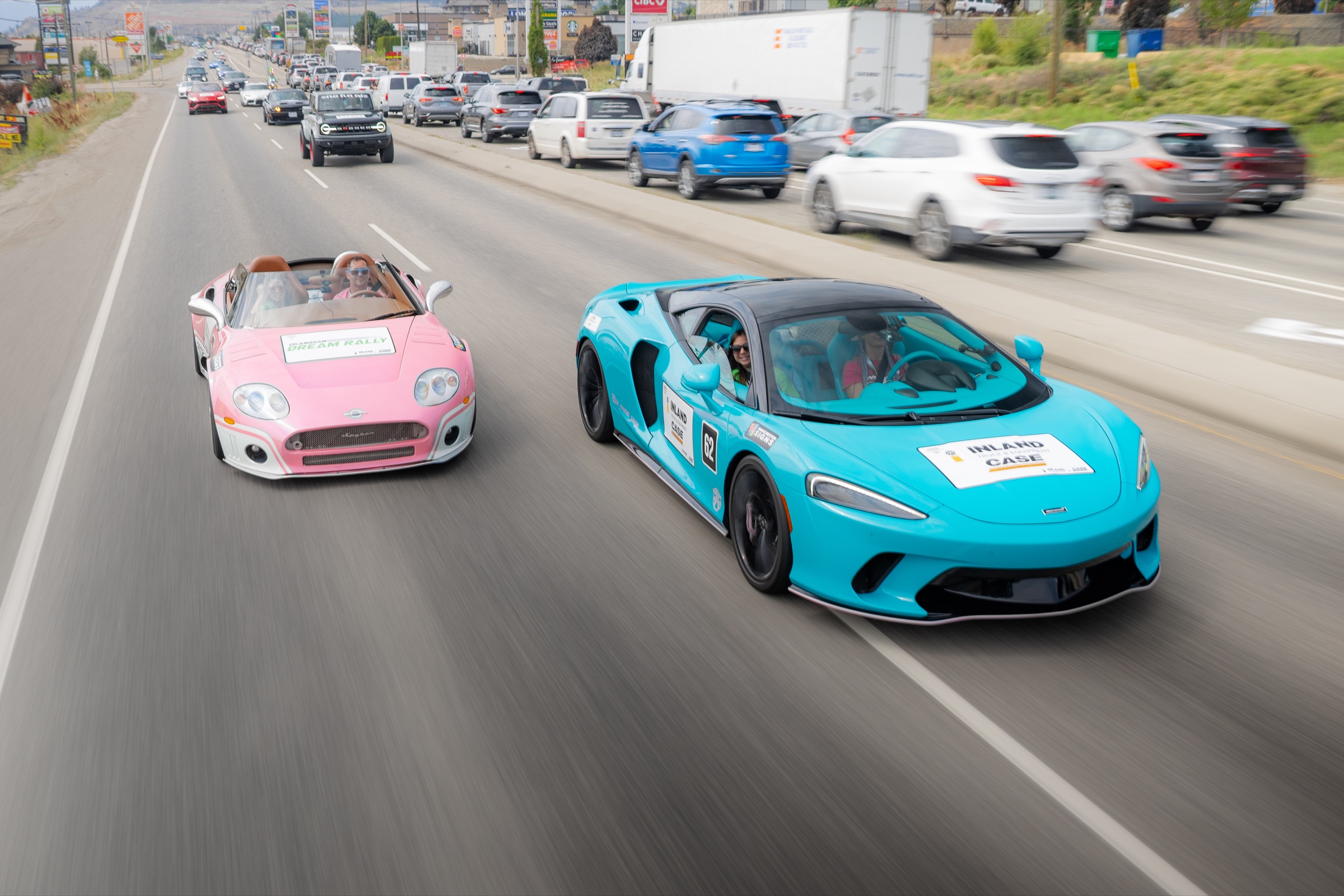 Turquoise McLaren and pink Spyker driving together in the rally