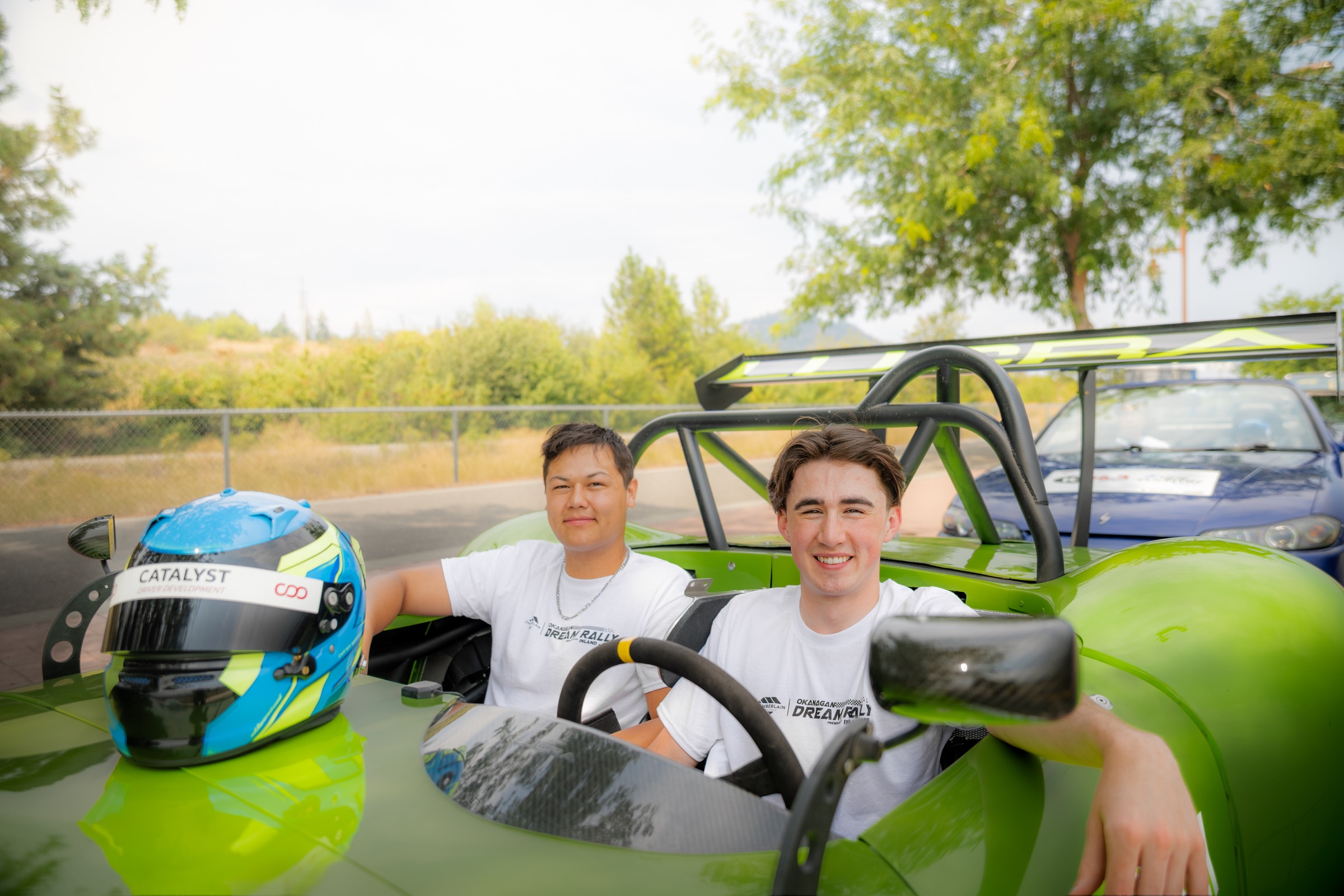 Dream Rally volunteers seated in a green track car with a racing helmet