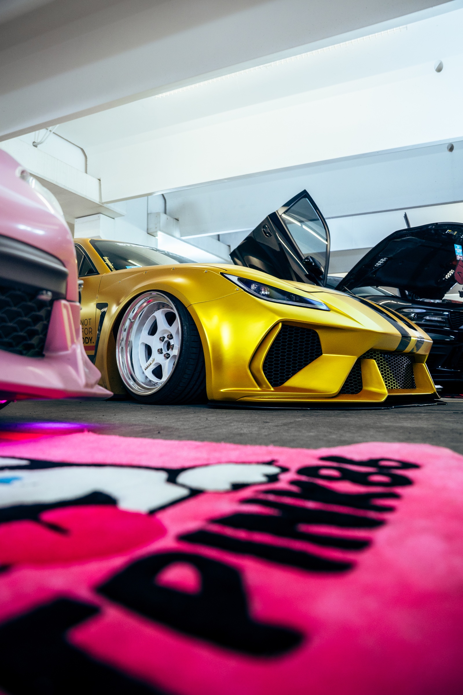 Gold custom sports car displayed beside a pink show car