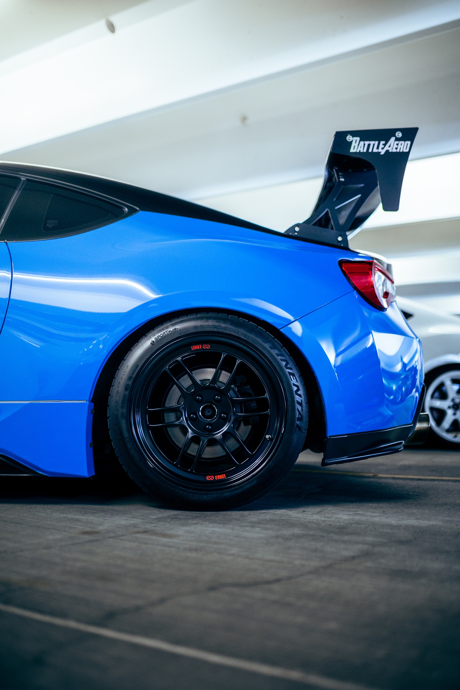 Rear wheel and wing detail on a blue sports coupe