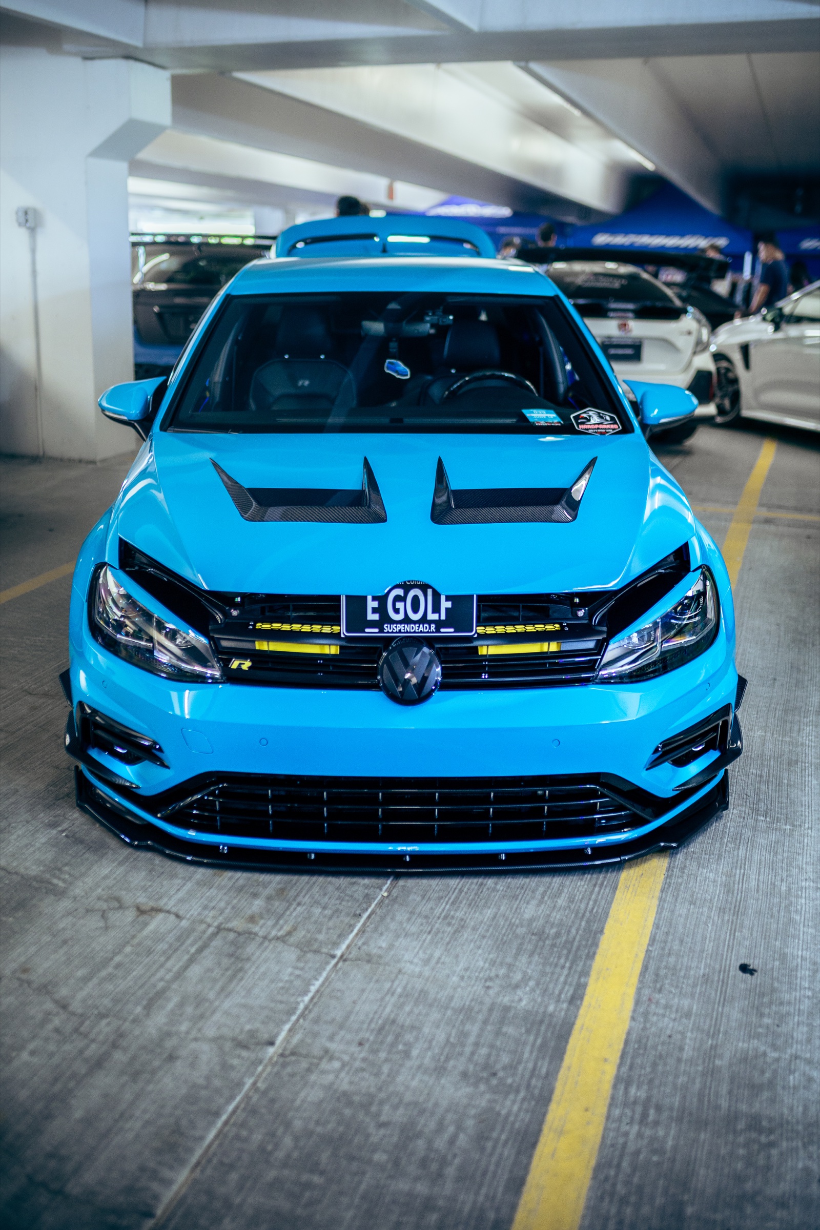 Blue Volkswagen Golf photographed head-on inside the show