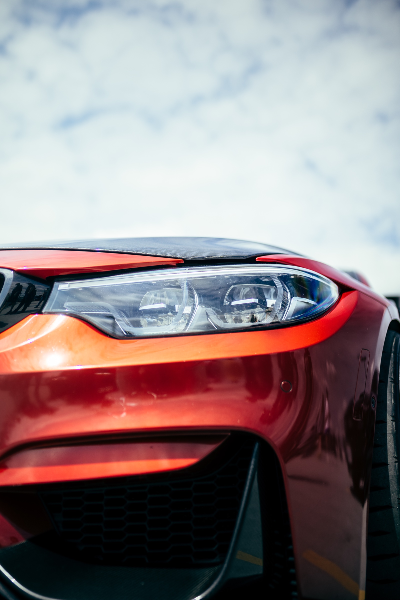 Headlight and carbon-fibre detail on a red BMW M3