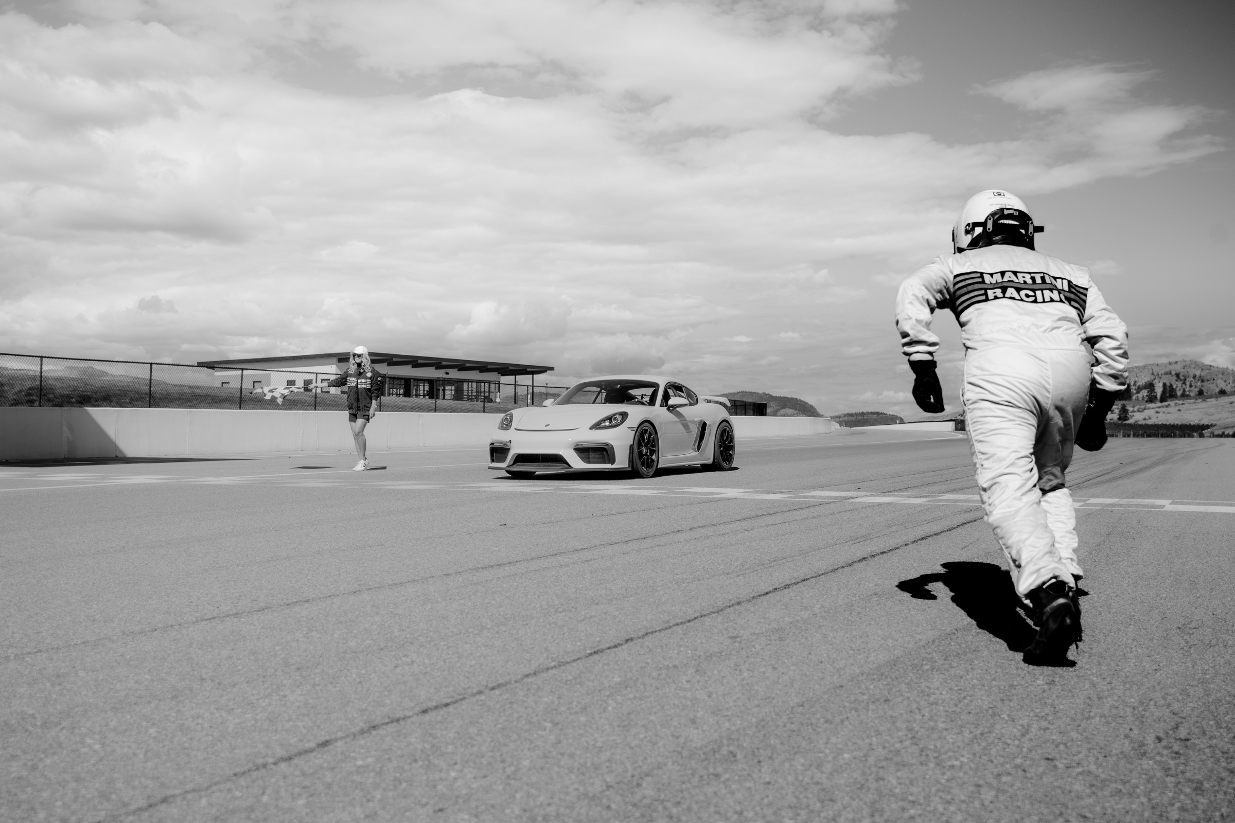 Black-and-white photograph of the driver running toward the Porsche GT4