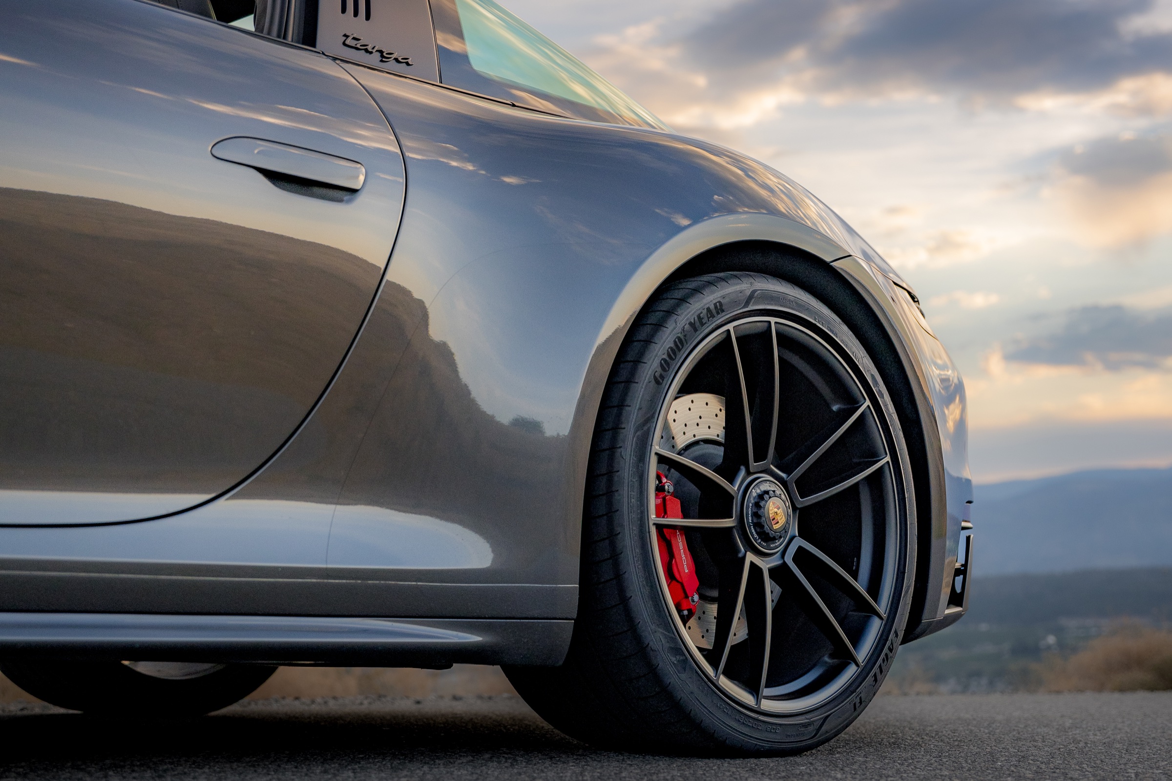 Porsche 911 GTS wheel, brake, and bodywork detail at sunrise