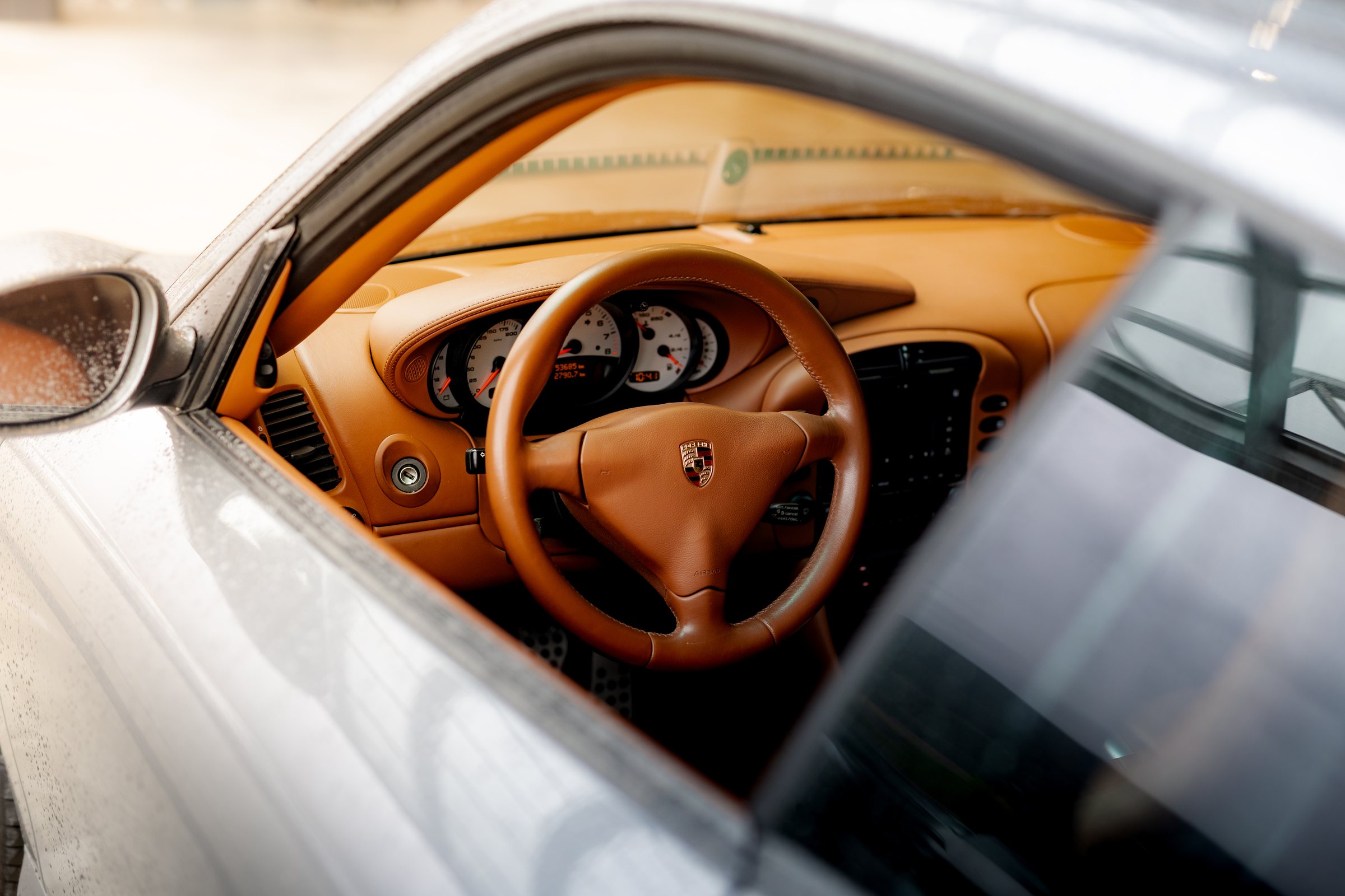Tan leather steering wheel and dashboard inside a classic Porsche