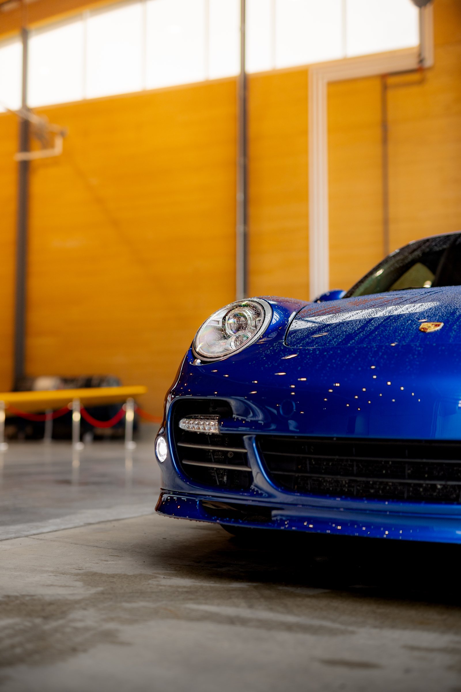 Blue Porsche photographed from the front inside the hangar