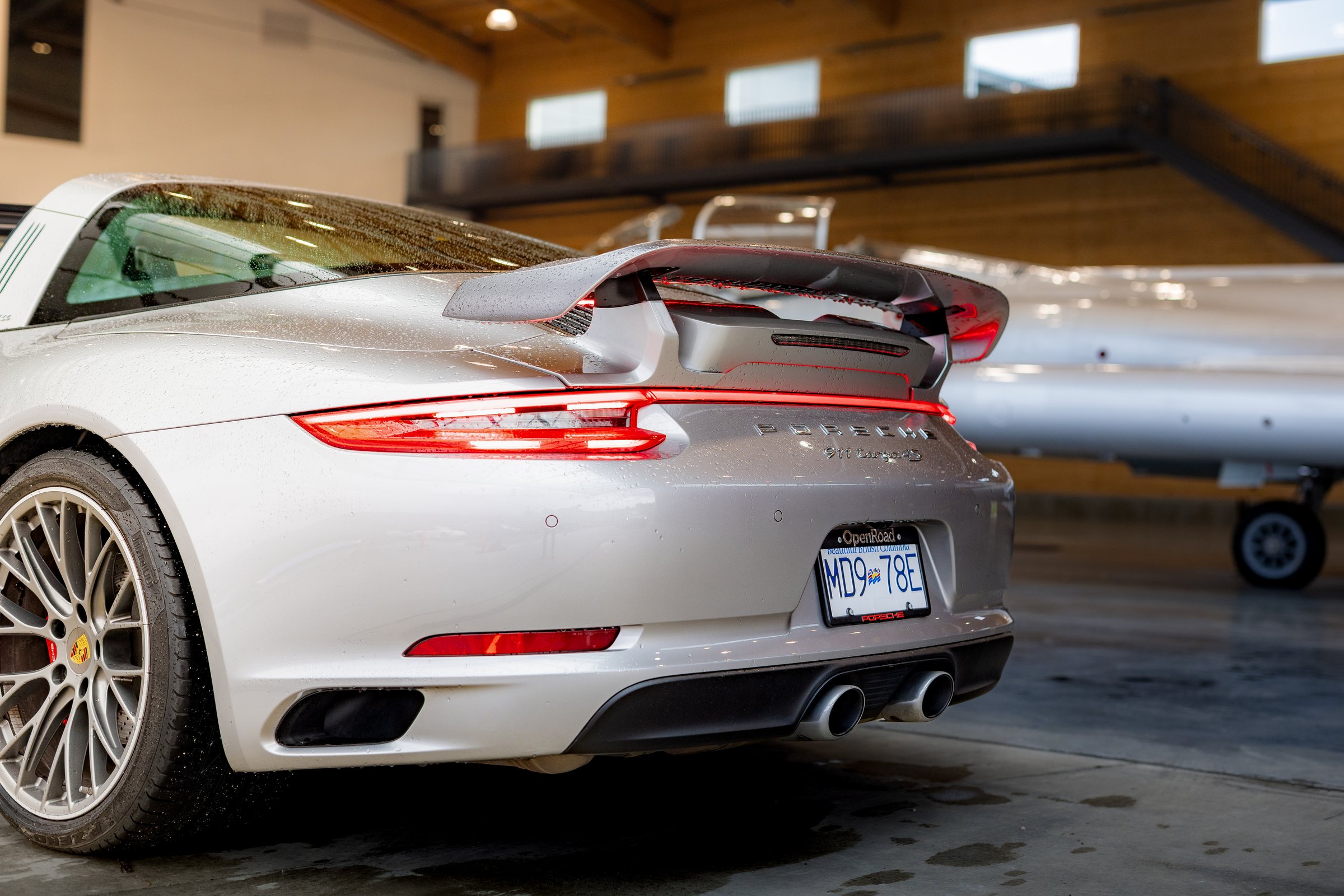 Silver Porsche 911 Targa 4S rear detail with aircraft beyond