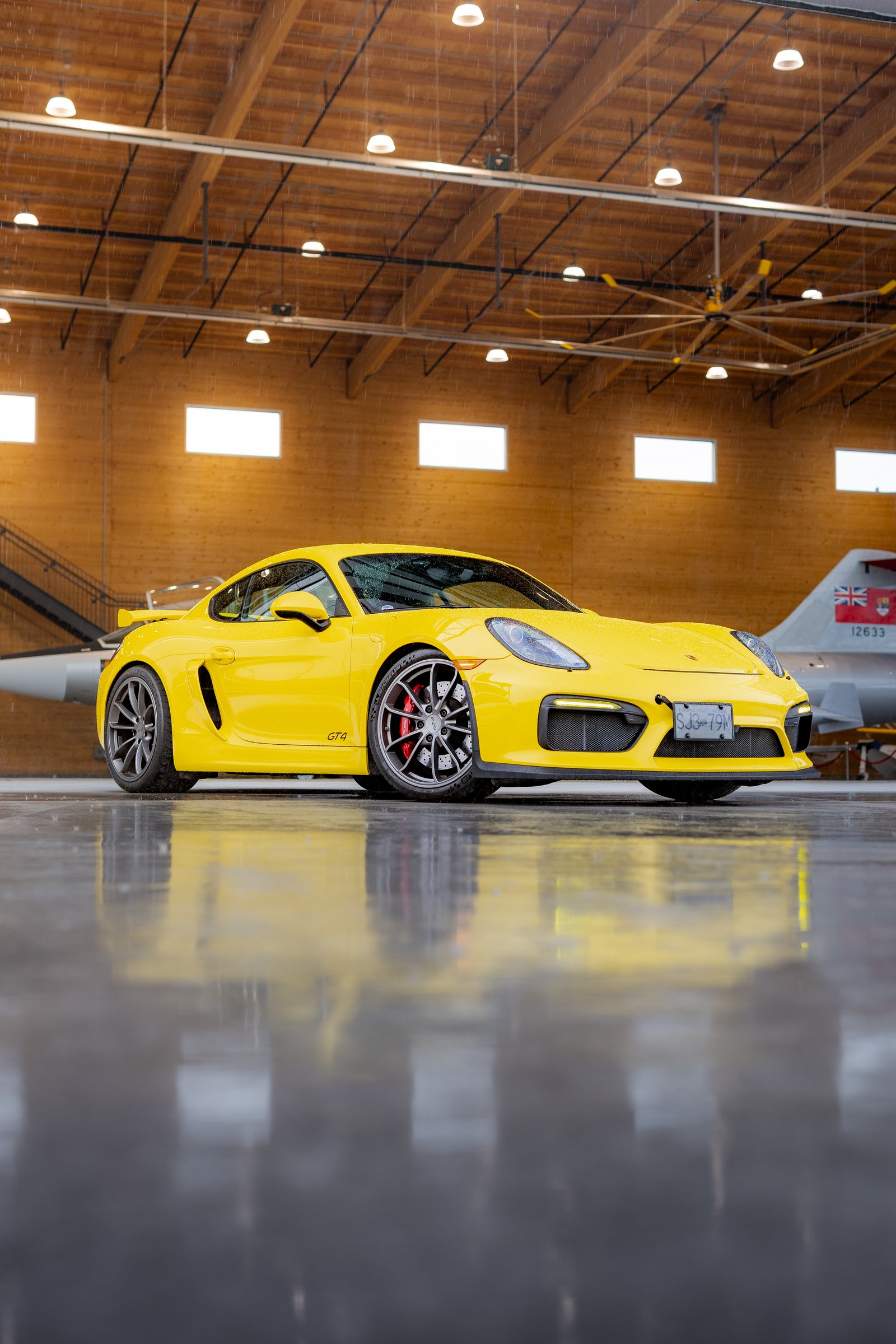 Yellow Porsche Cayman GT4 reflected on the hangar floor