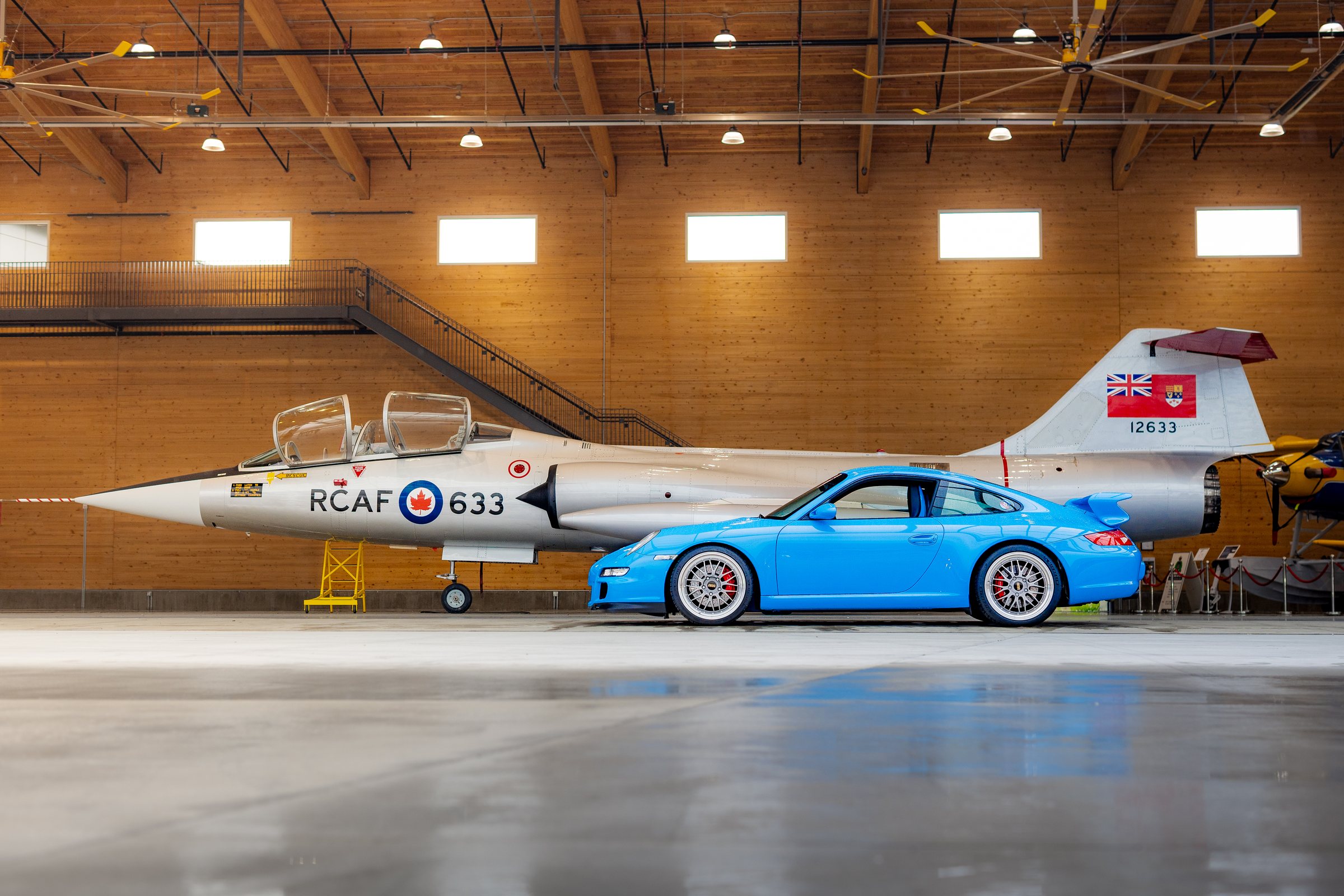 Blue Porsche 911 GT3 profiled beside an RCAF aircraft
