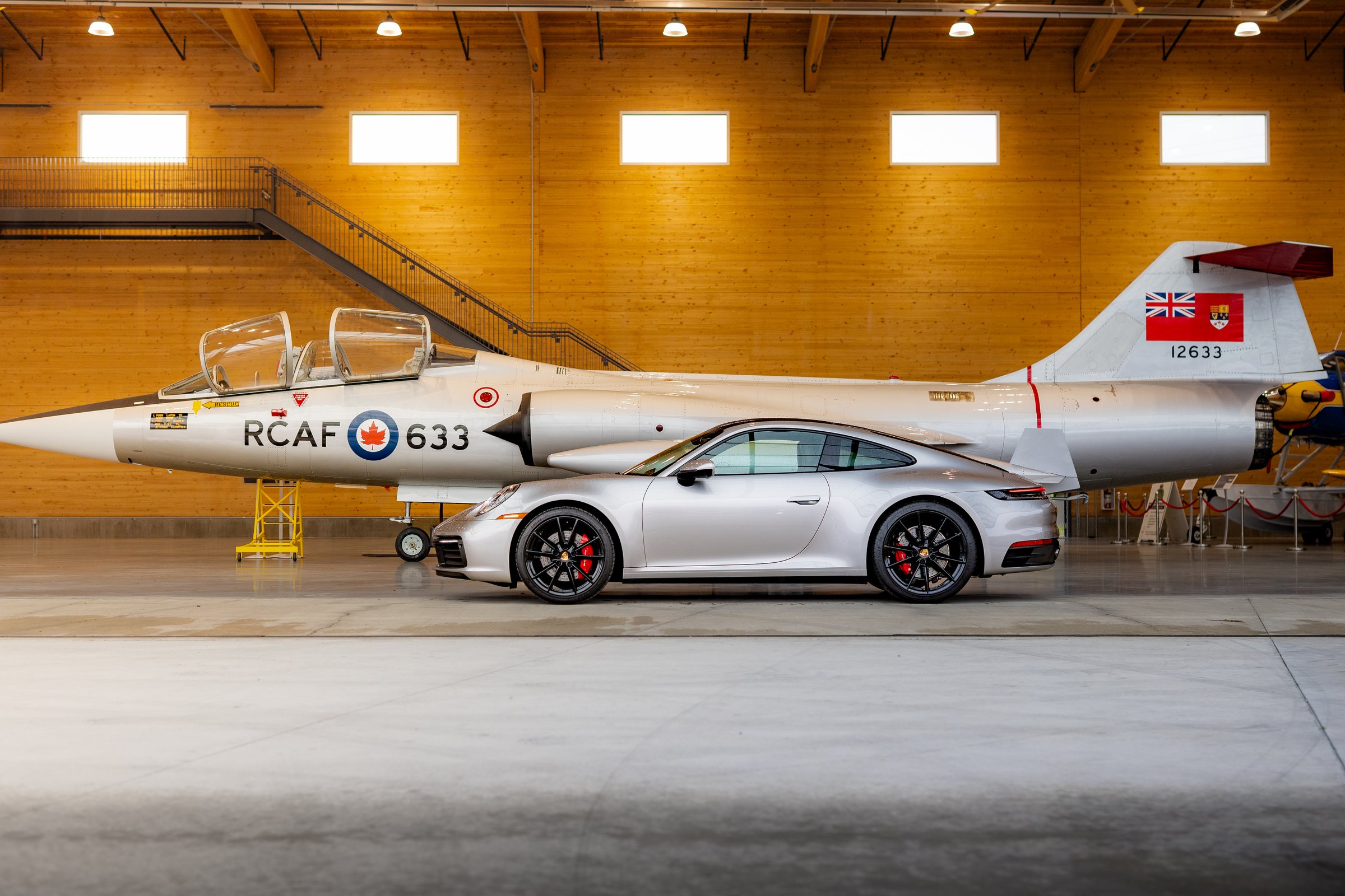 Silver Porsche 911 profiled beside an RCAF aircraft