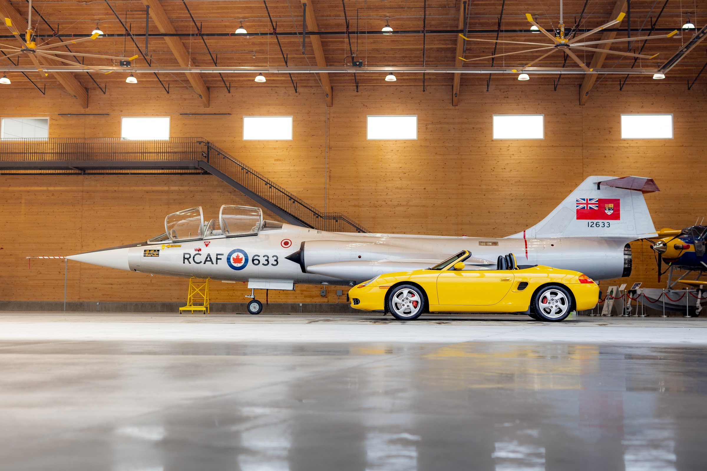 Yellow Porsche Boxster profiled beside an RCAF aircraft