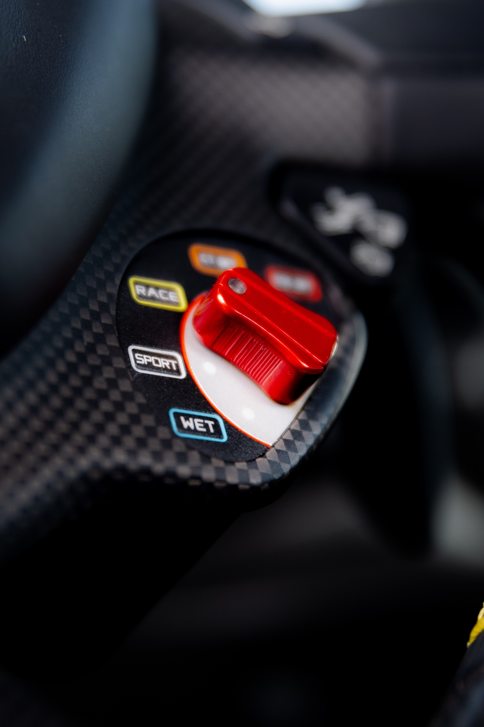 Red drive-mode selector set into a carbon-fibre steering wheel