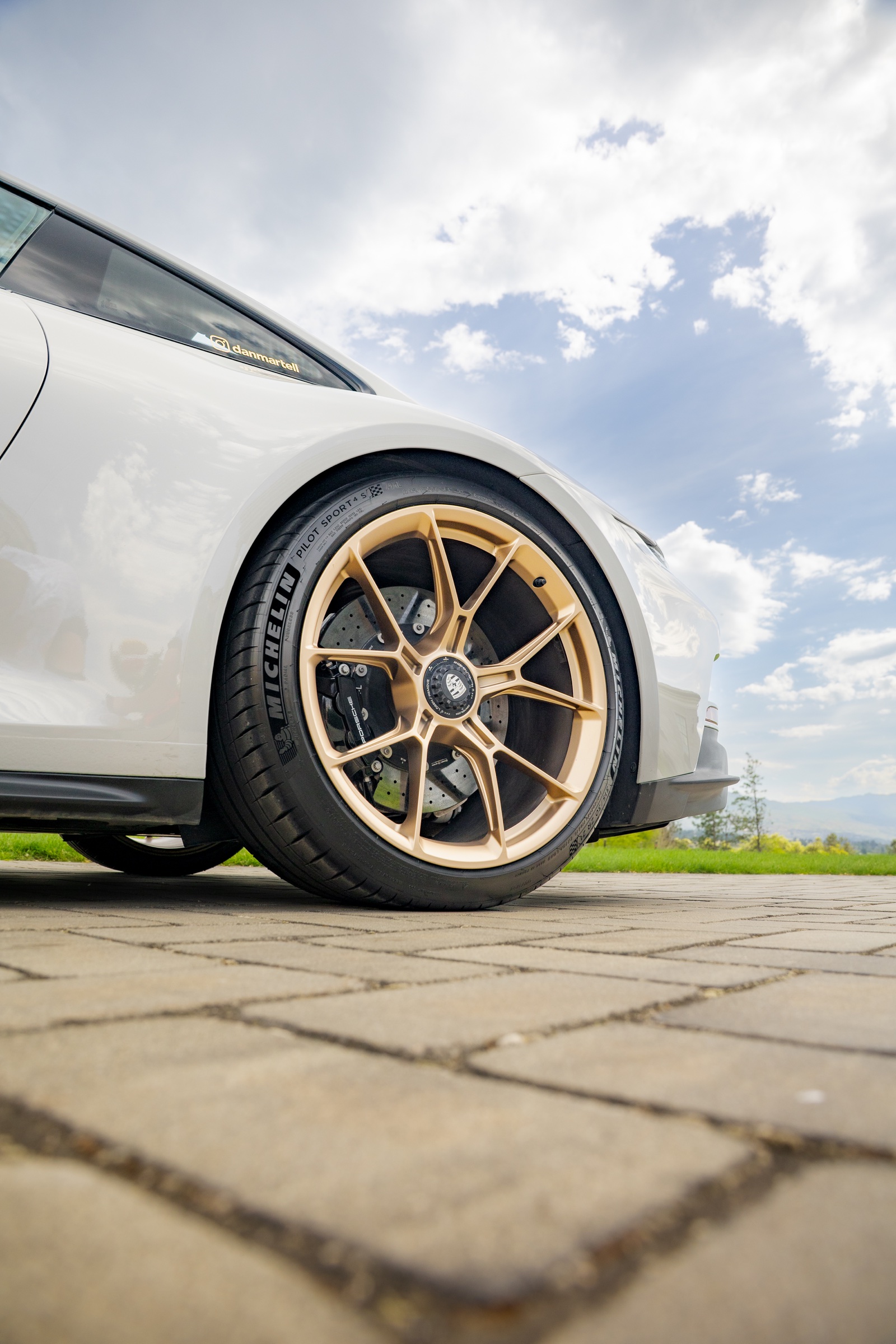 Gold Porsche centre-lock wheel and carbon-ceramic brake detail